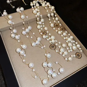 Elegant gold-tone multi-strand pearl necklace featuring a black camellia flower pendant