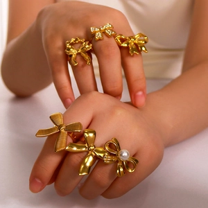 Golden bow ring set with pearls and zircons in various polished and textured styles