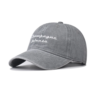 Close-up of grey washed cotton baseball cap with white 'Champagne please' embroidery