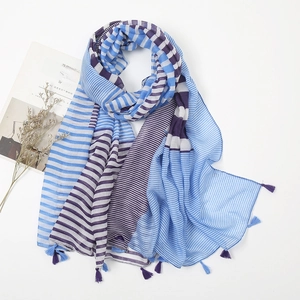 Close-up of lightweight purple and blue striped scarf with fringe tassels on white surface
