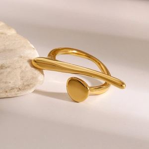 Macro shot of an irregular gold-plated stainless steel open ring on white stone