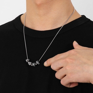 Detail of model wearing silver chain necklace with black square LOVE letter dice pendant