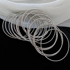 Macro detail of textured silver metal bangles with shimmering carved patterns