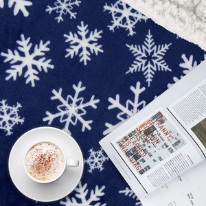 Detailed texture of blue Sherpa blanket with large white snowflake patterns and soft fleece