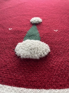 Détail macro du cache-pied de sapin rouge tricoté avec motif de sapin 3D vert et blanc