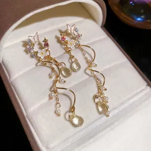 Elegant gold earrings with butterfly flowers, pearls, and teardrop crystal tassels