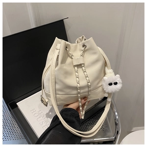 Detail of cream white bucket bag with chain drawstring and plush monster charm