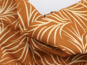 Macro shot of brown palm leaf print fabric detail on a sleeveless holiday maxi dress