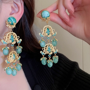 Détail de boucles d'oreilles baroques ajourées avec résine verte et cristaux brillants