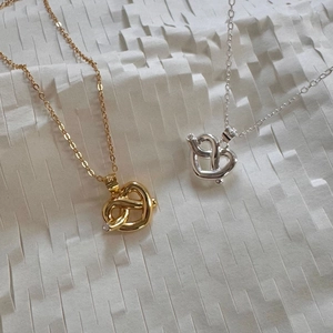 Macro view of gold and silver pretzel heart necklaces with sparkling crystal accents