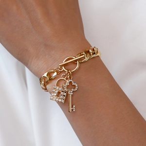 Close-up of golden chain bracelet featuring sparkling rhinestone lock and key charms