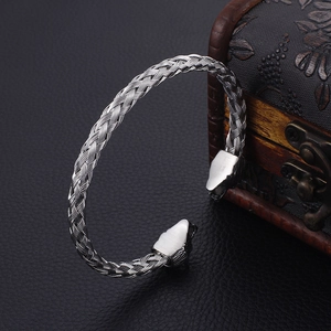 Detail of Viking wolf head braided steel bracelet on dark leather with wooden jewelry box