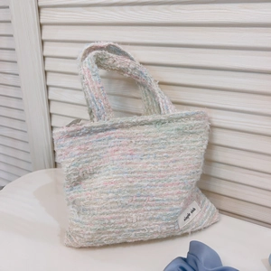 Dettaglio macro della trama in tweed arcobaleno di una piccola borsa con etichetta