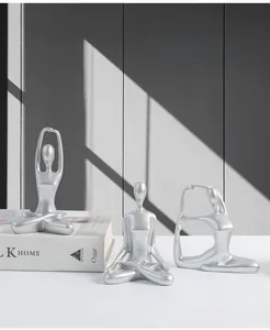 Detailed close-up of three modern silver yoga girl ceramic statues for home decor