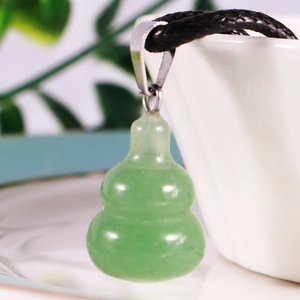 Detailed view of a green jade gourd pendant with a black braided cord on a white background