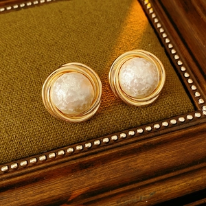 Macro detail of gold plated cotton pearl earrings with retro spiral texture finish