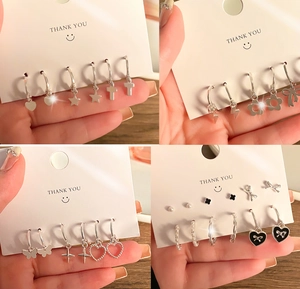 Detailed set of silver butterfly and pearl earrings on display cards with star motifs