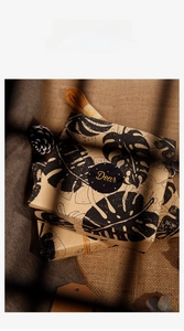 Macro view of kraft gift wrapping paper with black monstera leaf pattern and natural hemp rope