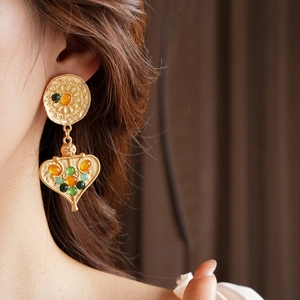 Close-up of vintage gold tassel earrings with colorful stones on a female model