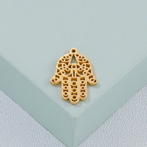 Golden Hamsa hand pendant with hollow design on a green geometric block