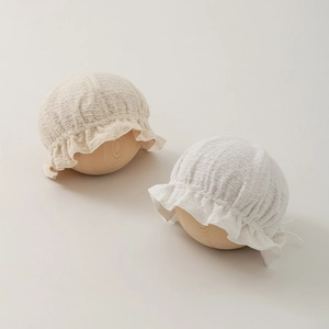 Close-up of soft lace cotton baby hats featuring delicate ruffle brims and hollow textures