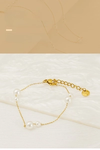 Detail of gold pearl link bracelet showing S.Steel tag and lobster clasp on wave background