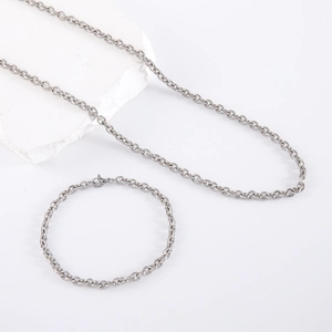 Polished stainless steel cable chain necklace and bracelet set on stone pedestal