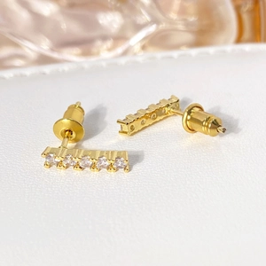 Macro shot of gold-plated rectangular bar studs with five inlaid white zircons
