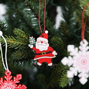 Wooden Santa Claus and snowflake ornaments hanging on a Christmas tree branch