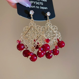Detail of vintage gold dangle earrings with red beads and hollow filigree design