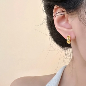 Gold-plated round hoop earrings with coin pattern on model with soft lighting