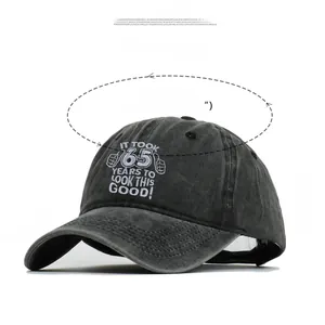 Detail showing 65th birthday embroidery on dark gray washed cotton baseball cap