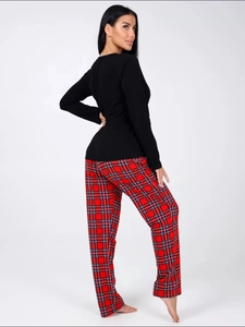 Detail of long sleeve black top and red plaid pajama pants set on female model