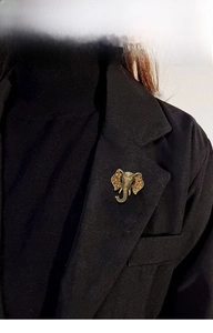 Macro detail of vintage elephant brooch with amber rhinestones on a black suit lapel