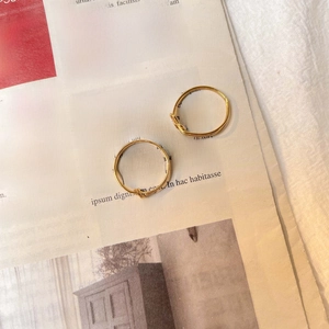 Close-up of minimalist gold twisted knot rings set on vintage newspaper and linen fabric