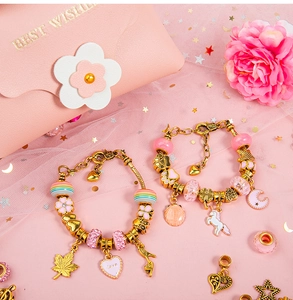 Detail of pink charm bracelets with unicorn pendants and love hearts on a pink mesh background