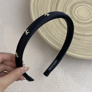 Detail of handmade black satin headband featuring delicate gold metal bow charms