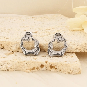 Détail macro de boucles d'oreilles lave argentées sur présentoir en travertin beige