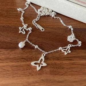 925 silver butterfly necklace with floral charms and pearl on wooden background