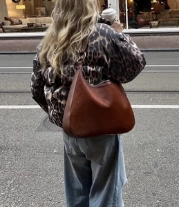 Outdoor-Aufnahme einer dunkelbraunen Hobo-Tasche aus Wildleder mit Leopard-Jacke kombiniert