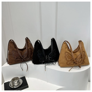 Three suede butterfly tote bags in dark brown, black and khaki on a white display stand