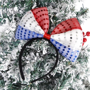 Detail of red white and blue sequin bow headband against snowy pine branch background