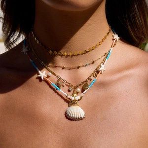 Bohemian multilayer gold necklace with shell and starfish charms worn by a model