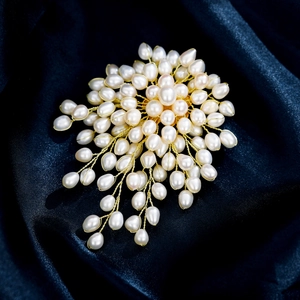 Detailed shot of handmade freshwater pearl brooch on dark blue silk background