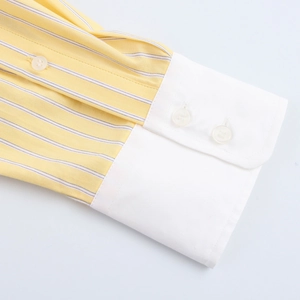 Detailed macro view of yellow and blue striped shirt cuffs with white button accents