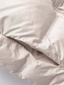 Detail of a creamy beige puffer vest showing the smooth fabric and zipper pocket macro view