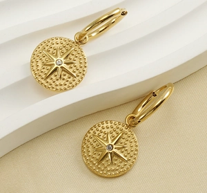 Détail de créoles en or 18 carats avec pendentifs étoile et cristal sur charms ronds