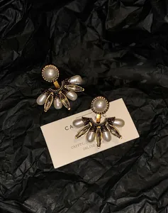 Détail de boucles d'oreilles vintage en éventail avec perles et cristaux sur fond noir