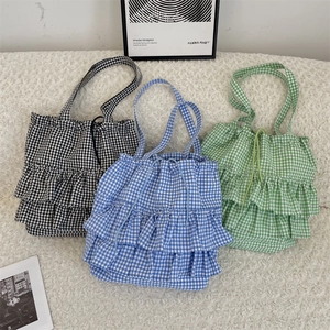 Detailed view of plaid canvas tote bags with layered ruffles in black, blue and green colors