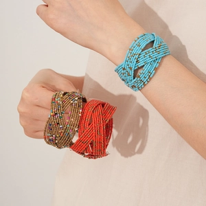 Détail de bracelets multicouches en perles tissées bleu ciel et rouge sur lin